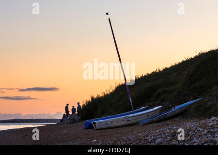 Sonnenuntergang am Strand von Ringstead Bay, Dorset, England, Großbritannien, einer Gruppe von Menschen gegen die untergehende Sonne Silhouette Stockfoto