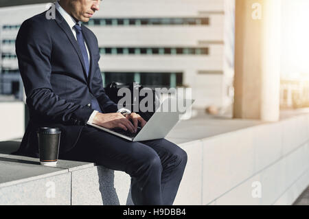 Geschäftsmann während der Eingabe auf seinem Notebook. Horizontal im Freien gedreht Stockfoto