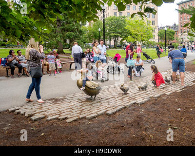 Kinder spielen am Bronze-Skulpturen von einer Ente und Entenküken von Nancy Schon in Erinnerung an das Buch "Make Way for Entenküken" von Robert McCloskey geschaffen. Stockfoto