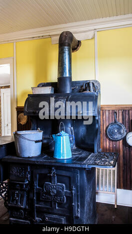 Landhausstil Küche Interieur mit einem antiken Kohleofen oder Holzofen mit einer Porzellan-Kaffeekocher und Eimer, Colorado, USA, Winter Interieur Stockfoto