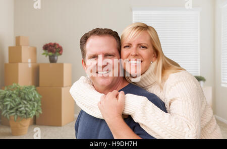 Glückliches junges Paar im leeren Raum mit gepackten Kisten und Pflanzen. Stockfoto