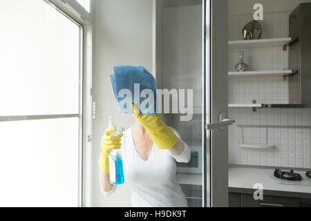 Junge Frau, die die Fenster putzen Stockfoto