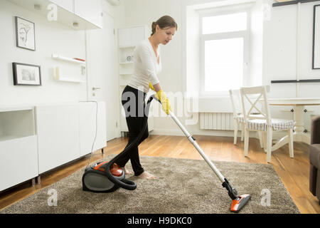 Frau in Freizeitkleidung Vakuum Reinigung des Teppichs Stockfoto