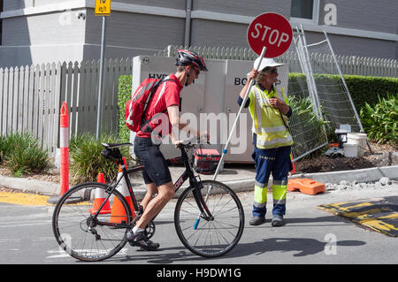 Radfahrer, die warten auf Baustellen Stop-Schild, South Bank Parklands, Stadt Brisbane, Brisbane, Queensland, Australien Stockfoto