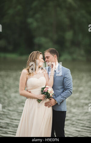 Schöne Hochzeit, paar, Braut, Bräutigam küssen und posieren auf der Brücke in der Nähe von See Stockfoto