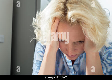 Weibliche blonde Dame mit Kopf in Händen suchen besorgt Stockfoto