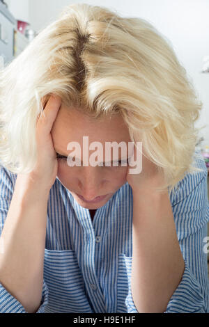 Weibliche blonde Dame mit Kopf in Händen suchen besorgt Stockfoto