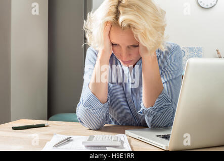 Weiblich mit Kopf in Händen verzweifelt, während Konten zu tun Stockfoto