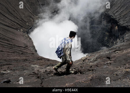 Tenggerese Mann zu Fuß auf den Rand eines aktiven Vulkans im Bromo Tengger Semeru National Park. 17. Januar 2014 - Java, Indonesien Stockfoto