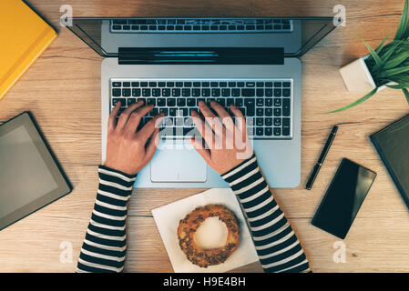 Büroalltag, weibliche Hände arbeiten auf Laptop-Computer - Draufsicht der Geschäftsfrau Eingabe Tastatur mit anderen mobilen Elektronik auf Arbeitsbereich d Stockfoto