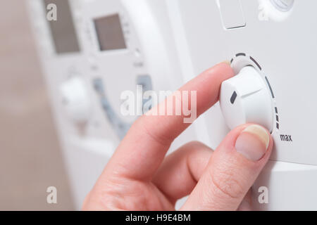 Finger passen Sie das Rad auf einem weißen Kessel oder Elektrogerät. Es scheint, drehen in Richtung zu den MAX-Einstellung.  Andere Tasten und eine digitale disp Stockfoto