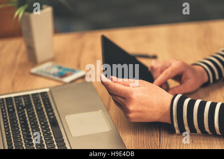 Frau mit digitalen Tablet-Computer im Büro, Laptop und Handy sind auch auf Desktop platziert. Stockfoto