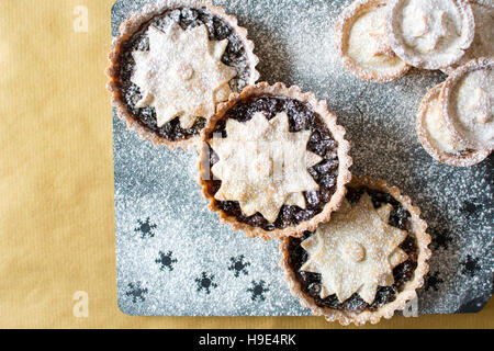 Weihnachten-Hackfleisch-Kuchen, mit einem Stern verziert und mit Puderzucker auf Schiefer und gold Hintergrund abgestaubt Stockfoto