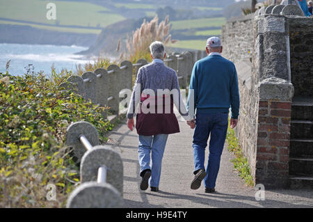 Ein älteres Ehepaar zu Fuß entlang der Strandpromenade in Falmouth, Cornwall Stockfoto