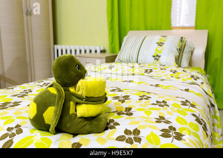 Kuscheltier Schildkröte mit einem Handtuch auf dem Bett Stockfoto