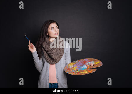 Angenehme nachdenkliche Frau mit Farbpalette. Stockfoto