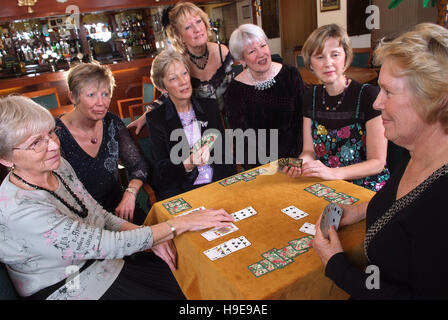 Eine Gruppe von sieben Frauen-Bridge-Spieler, die an einem einzigen Tisch sitzen. Stockfoto