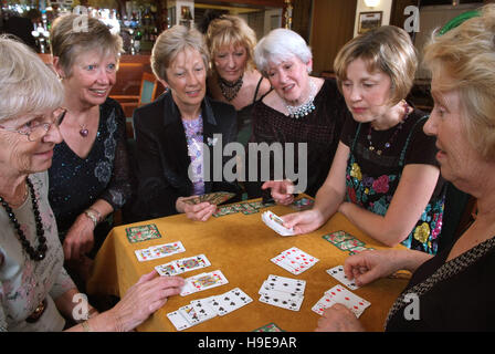 Eine Gruppe von sieben Frauen-Bridge-Spieler, die an einem einzigen Tisch sitzen. Stockfoto