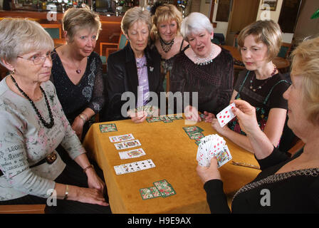 Eine Gruppe von sieben Frauen-Bridge-Spieler, die an einem einzigen Tisch sitzen. Stockfoto