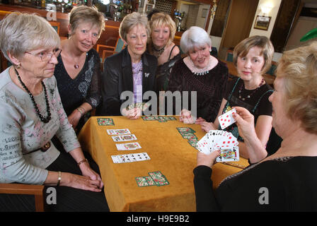 Eine Gruppe von sieben Frauen-Bridge-Spieler, die an einem einzigen Tisch sitzen. Stockfoto