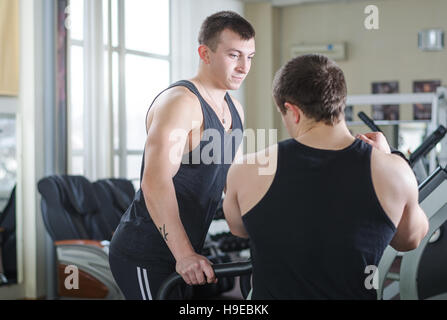 Der Coach unterstützt den Sportler auf einem Laufband im Fitnessstudio Stockfoto