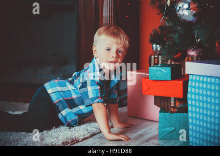 Schöne Portrait eines kleinen Jungen auf dem Hintergrund der Gaben in das neue Jahr, das Zimmer unter den Weihnachtsbaum. Die Idee für Postkarten. Soft Focus Stockfoto