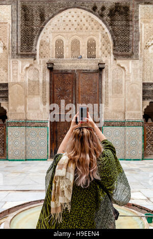 Eine weibliche Touristen nimmt A Foto mit A Smartphone In der Medersa Bou Inania, Fes el Bali, Fes, Marokko Stockfoto