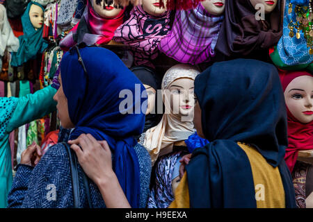 Zwei junge Frauen suchen bei Kopftücher für Verkauf an A Shop In The Medina, Fes el Bali, Fes, Marokko Stockfoto