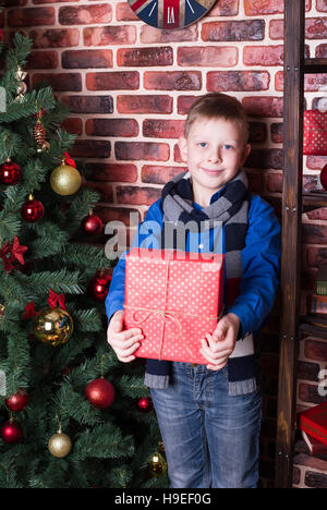 Ein Junge hält ein Geschenk beim stehen in der Nähe von the Christmas tree Stockfoto