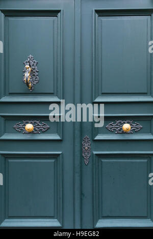 Ein dunkles Grün bemalte hölzerne Tür einer Villa mit eleganten Metallverzierungen, goldene Knöpfe und Klopfer. Stockfoto