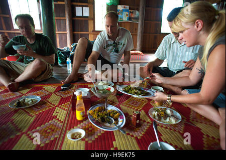 Ausländer essen Mittagessen in eine Community-basierte Home Aufenthalt auf Koh Trong, einem verarmten Insel im Mekong in Kambodscha. Stockfoto