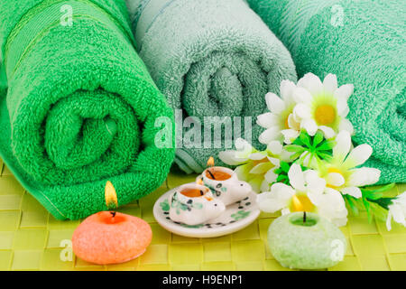 Bad mit Handtüchern, Kerzen und Blumen auf Bambus Hintergrund gesetzt. Stockfoto