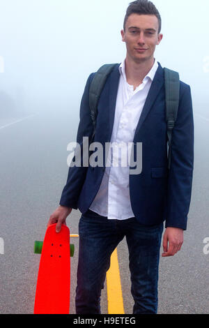 Kaukasischen Mann mit kleinen roten Skateboard im Nebel Stockfoto