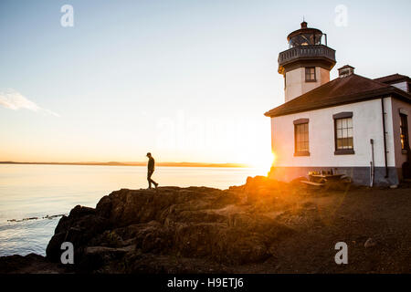 Silhouette des kaukasischen Mann zu Fuß auf Felsen in der Nähe von Leuchtturm Stockfoto