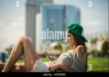 Kaukasische Frau Verlegung in Grass SMS auf Handy Stockfoto