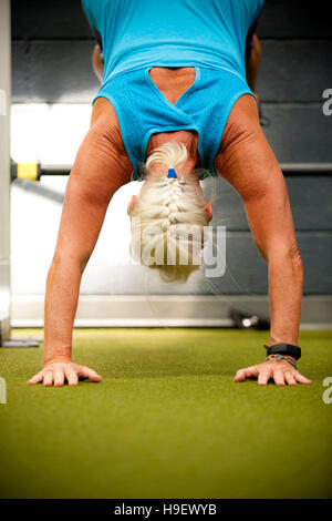 Ältere Frau tun Handstand im gymnasium Stockfoto