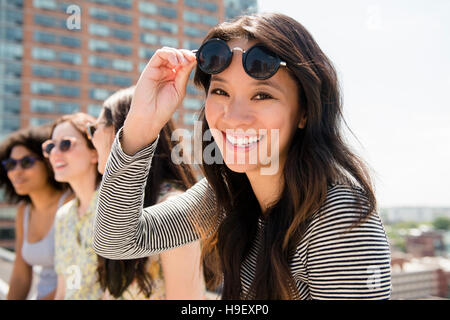 Lächelnde Frau heben Sonnenbrille im freien Stockfoto