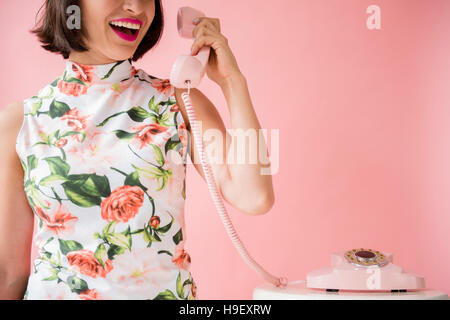 Hispanische Trägerin geblümten Kleid mit rosa Telefon Stockfoto