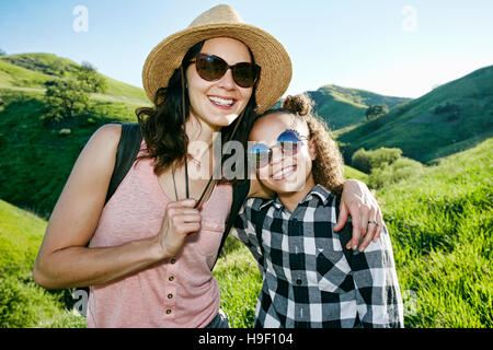 Lächelnde Mutter und Tochter mit Sonnenbrille auf Hügel Stockfoto