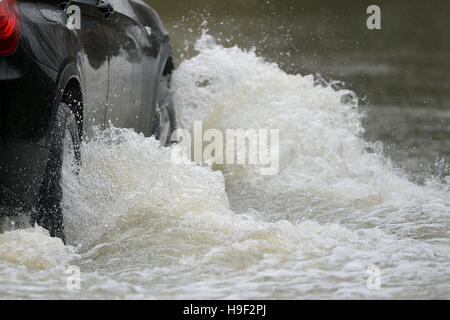 Ein Auto fährt durch Hochwasser in Sileby Leicestershire nach starkem Regen über Nacht, wie Wind und Regen Knollenfäule Teile von Großbritannien droht weitere Reisechaos weiterhin nach Starkregen Blitz-Überschwemmungen und Störungen in den meisten Teilen des Landes verursacht. Stockfoto