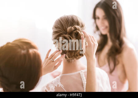 Angenehme Brautjungfern helfen die Braut mit ihrer Frisur Stockfoto