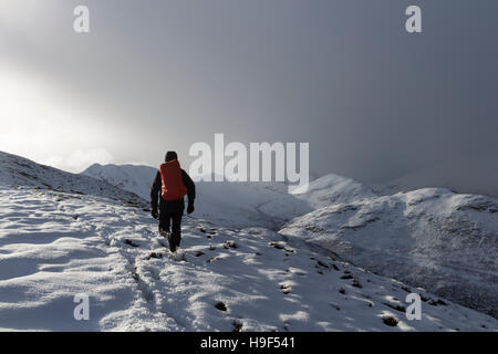 Walker auf der Piste Barrow mit Bergen von Causey Hecht, Segel und Crag Hill wird umhüllt von nähert sich Schneesturm, Lake District von Cumbria Stockfoto