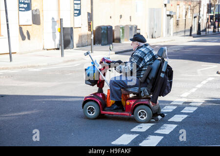 Ein älterer Mann ein Elektromobil auf der Straße fahren Stockfoto