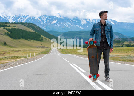 Longboarder posiert neben seinem Longboard Skateboard auf der Bergstrasse. Stockfoto