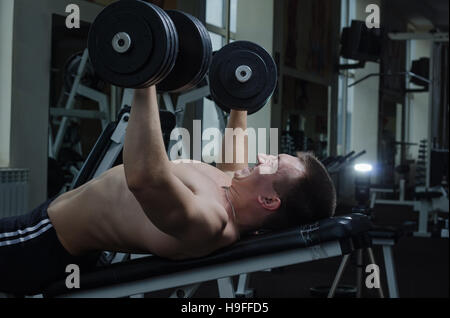 Jungen muskulöser Mann führt eine Hantel Brustpresse auf eine Schrägbank in der Turnhalle Stockfoto