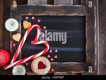 Chalk Board und herzförmige Bonbons und Kekse am Valentinstag Hintergrund mit Textfreiraum Stockfoto