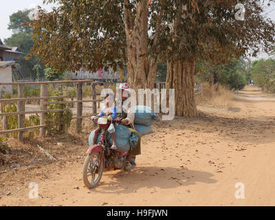 Kambodscha, Stung Treng Katot Dorf, von Brao Stamm bewohnt. Frau und Kind auf Motorrad, tragen Säcke Reis. Sean Sprague Foto Stockfoto