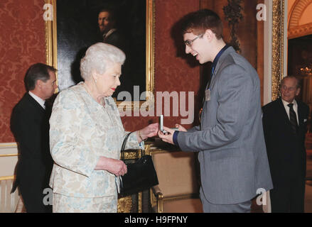 Königin Elizabeth II vergibt Tyler Bailer, 17, aus Kanada, mit Russell Medal im Rahmen eines Empfangs für die königlichen Leben sparen Gesellschaft am Buckingham Palace, London statt. Stockfoto