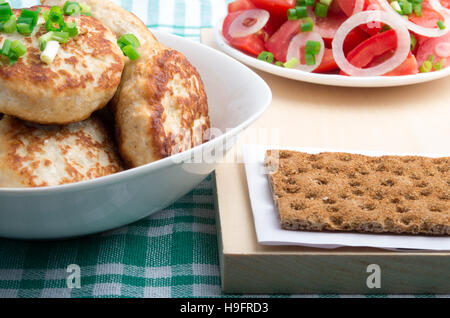 Hähnchen Schnitzel, Salat aus frischen Tomaten und Roggen Keks Nahaufnahme auf einer grünen Tischdecke Stockfoto