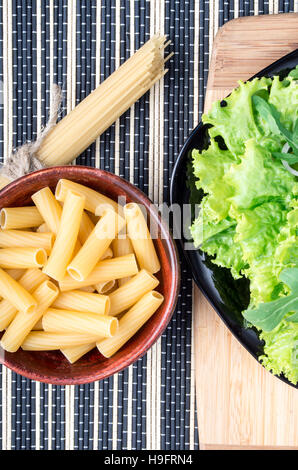 Draufsicht auf die Zutaten zum Kochen gesunde Ernährung - Spaghetti, Pasta und Salat auf einem Holzsockel auf der Oberfläche des Tisches Stockfoto